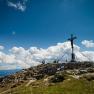 Gipfelkreuz auf dem Dürrenstein mit Wanderern und Wolken am Himmel.