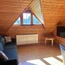 Gem&uuml;tliches Wohnzimmer in einer Dachgeschosswohnung mit Holzverkleidung, Sofa, Fernseher und Dachfenster.