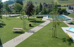 Gr&uuml;ne Parkanlage mit Schwimmbecken und Sitzb&auml;nken.