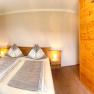 Gem&uuml;tliches Schlafzimmer mit Doppelbett, Holzm&ouml;beln und angrenzendem Badezimmer mit Dusche.